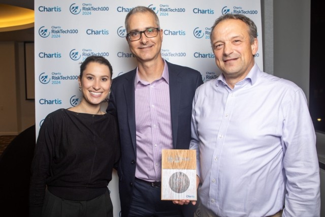 Three people standing in a row holding an award